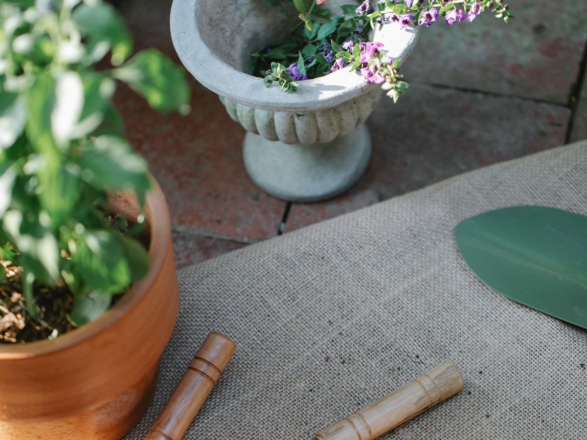 Garden hand tools and a planted stone urn on a terrace